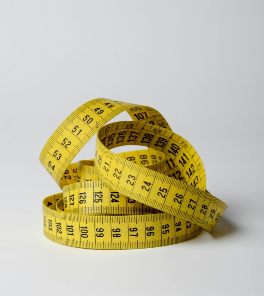 Mastering Measurements: A Guide to Taking Precise Measurements (Free Downloads) A close-up image of a coiled yellow measuring tape displaying numbers clearly.